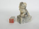 statue of a dog sitting on a box next to a small box with a chinese writing on it