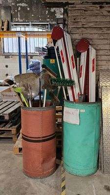 Plusieurs paires de skis et de bâtons de ski sont empilés dans un local de rangement