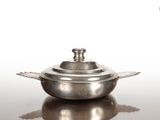 une casserole en argent avec un couvercle, posée sur une table