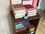 several books are stacked on top of a wooden shelf in a room