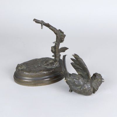 sculpture en bronze représentant un oiseau perché sur une branche, tenant une loupe