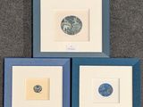 trois œuvres d'art encadrées, bleues et blanches, sur un fond gris