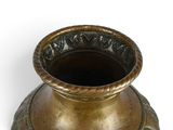 a gold vase that is sitting on a white surface
