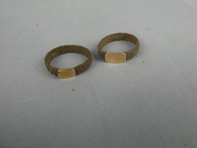 une paire de bagues dorées posées sur un fond blanc