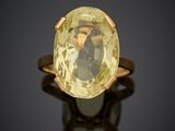 a close up of a ring with a yellow stone on a black surface