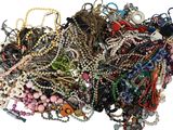 a pile of assorted necklaces and bracelets on a white surface