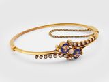 a close up of a gold bracelet with blue and white stones