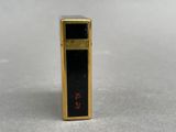 an image of a gold and black lighter sitting on top of a table