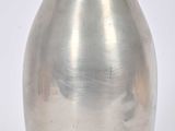 un vase en argent posé sur une surface blanche