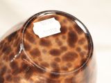 a brown vase with a label on it sitting on a table