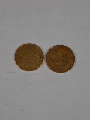two gold coins sitting side by side on a white surface