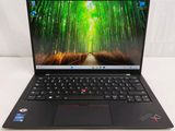 the laptop is open on a white surface with green trees in the background