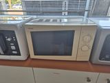 three microwaves sitting on top of a wooden counter next to a window