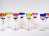 six verres à vin colorés alignés en rang sur une surface blanche