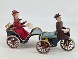 two figurines of a man and a woman riding in a carriage