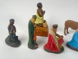 five figurines of people sitting on a bench