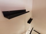une étagère noire fixée au mur au-dessus de l'escalier