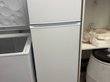 a white refrigerator and a white trash can in a room