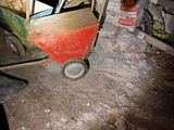un petit chariot rouge posé au milieu d'une pièce sale