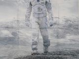 affiche représentant un homme en combinaison spatiale debout devant une montagne