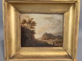 un tableau représentant un paysage, dans un cadre doré, sur fond gris