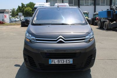 une camionnette Citroën garée sur un parking devant un immeuble