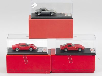 trois modèles réduits de voitures rouges dans des vitrines posées sur un fond blanc