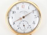 a close up of a gold pocket watch on a white surface