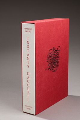 un livre rouge posé sur une table blanche, près d'un mur gris