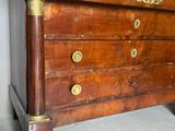 une commode en bois avec un plateau en marbre, posée sur un sol carrelé