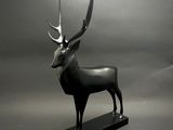 statue d'un cerf avec des bois, posée sur un socle noir