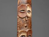a carved wooden mask with two faces and two eyes