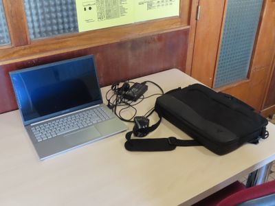 a laptop computer sitting on a desk next to a bag