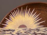 a brown plate with a white and yellow sun on it