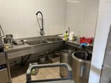 une grande cuisine en inox équipée d'un évier et d'une poubelle
