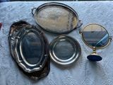 trois plateaux en argent et un miroir posés sur une table