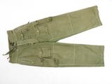 une photo d'un pantalon de treillis militaire posé sur une surface blanche
