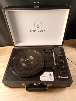 une valise ouverte contenant un tourne-disque, posée sur une table en bois
