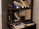 une bibliothèque noire sur laquelle sont posés des livres, dans une pièce