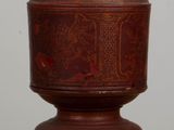a small wooden object on a table with a white wall in the background