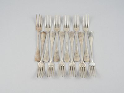 six fourchettes posées sur une table blanche