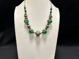 a white mannequin with green beads and silver beads