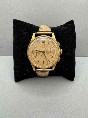 an image of a gold watch sitting on a black velvet cushion