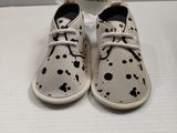 white shoes with black spots on them sitting on a white surface