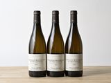 three bottles of wine sitting on top of a wooden table
