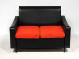 une image représentant un canapé en cuir noir avec des coussins orange sur fond blanc