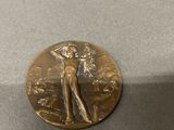 a gold medal with a woman on it sitting on a table