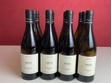 Quatre bouteilles de vin sont posées sur une table devant un mur rouge.