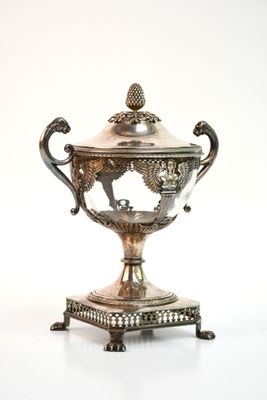 une coupe en argent posée sur un socle, sur une surface blanche