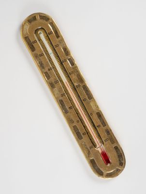 an old brass thermometer on a white surface with a red light